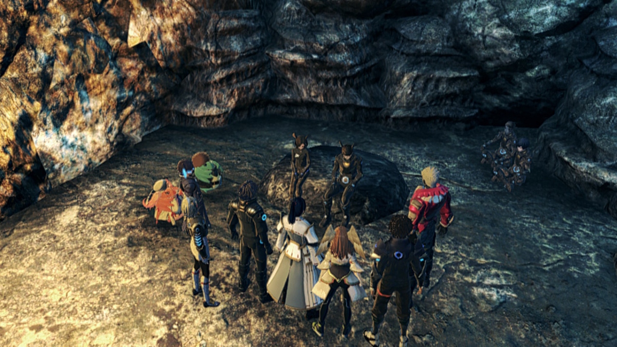 Un groupe de personnages dans une variété de tenues différentes se tient en demi-cercle autour de deux personnes en costume de soldat similaire assis sur un rocher à l'intérieur d'une grotte