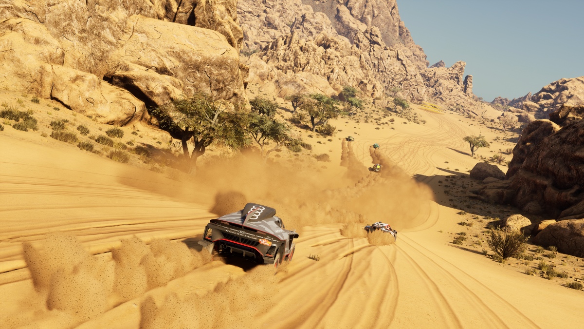 Plusieurs voitures en course dans une vallée rocheuse du désert
